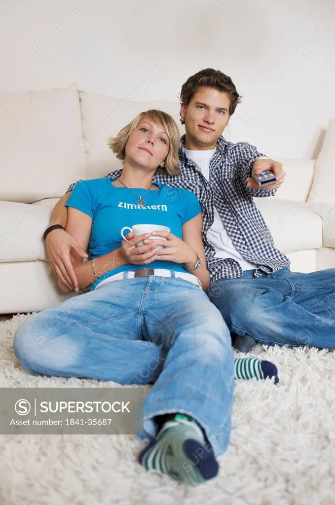 Teenager couple sitting in front of couch and watching television, low_angle view