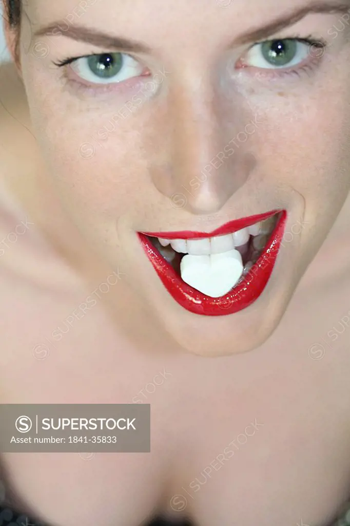 Close_up of young woman eating heartshape candy