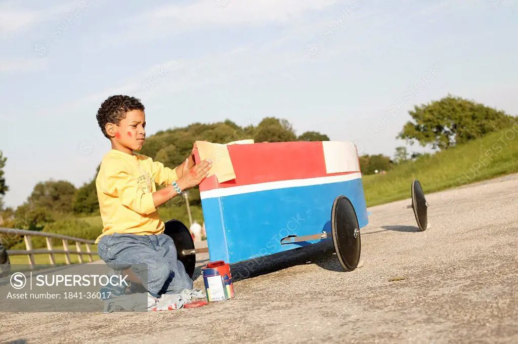 Boy cleaning soapbox on road