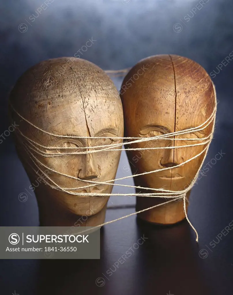 Close_up of two cracked wooden face tied up with threads