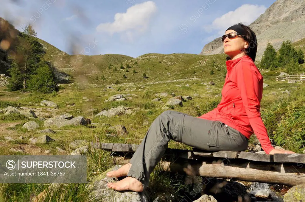 Mid adult woman sitting on footbridge, Trentino_Alto Adige, Italy