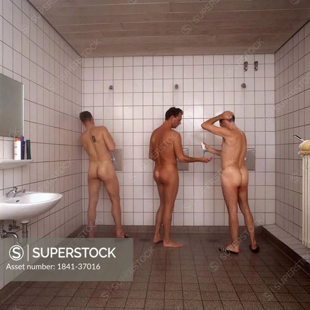 Rear view of three naked men taking shower