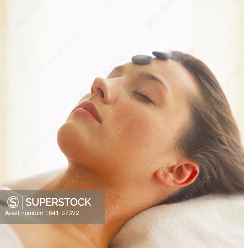 Close_up of young woman receiving hot stone treatment