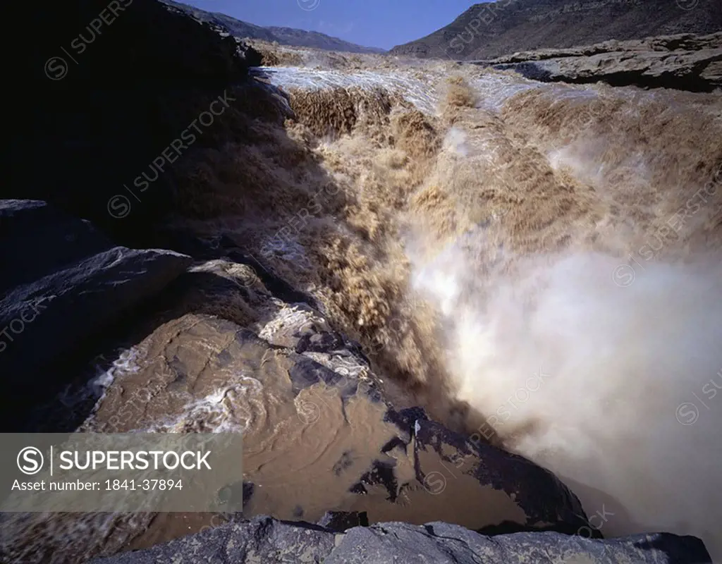 Muddy river water cascading over rocks, Hukou Falls, China