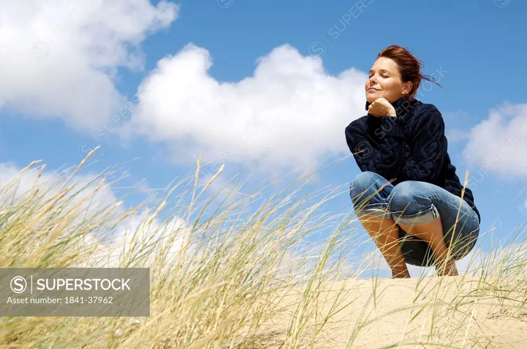 Low angle view of young woman crouching on beach