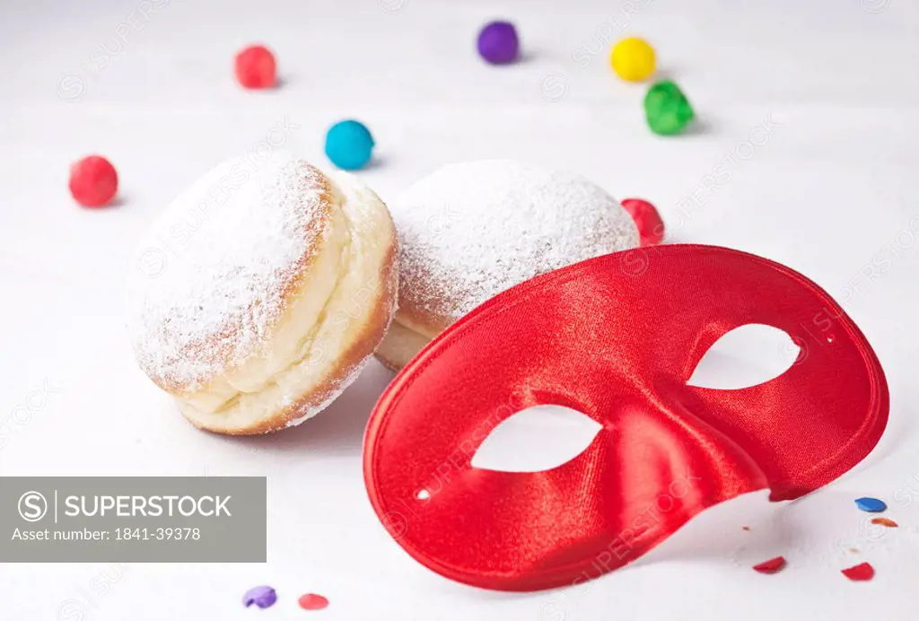 Red carnival mask, doughnuts and confetti, close_up