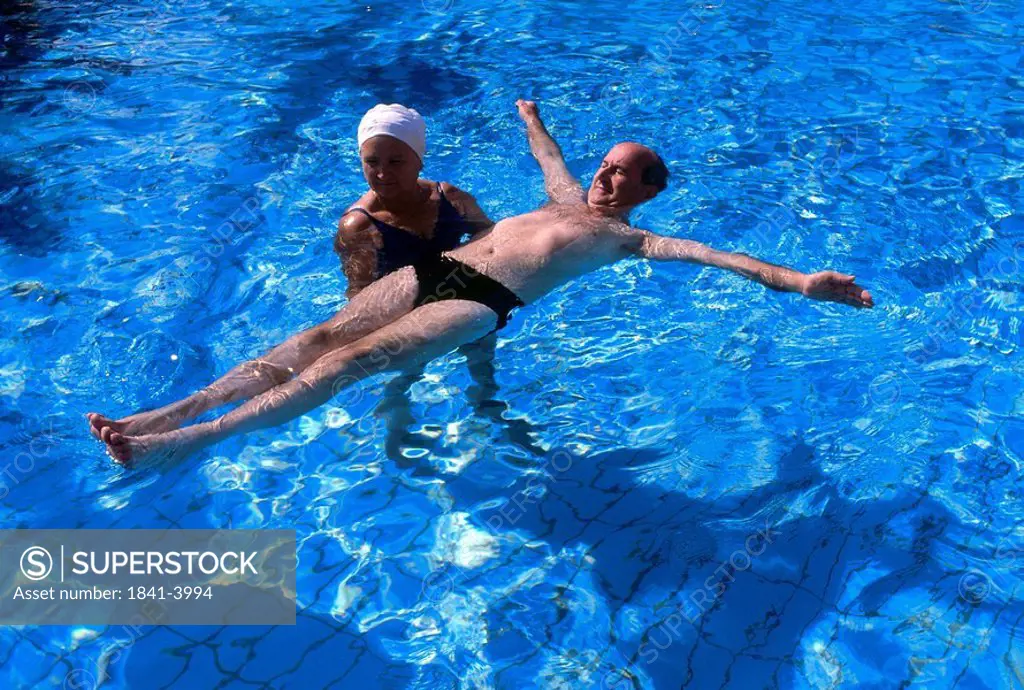 High angle view of woman teaching man to swim in swimming pool