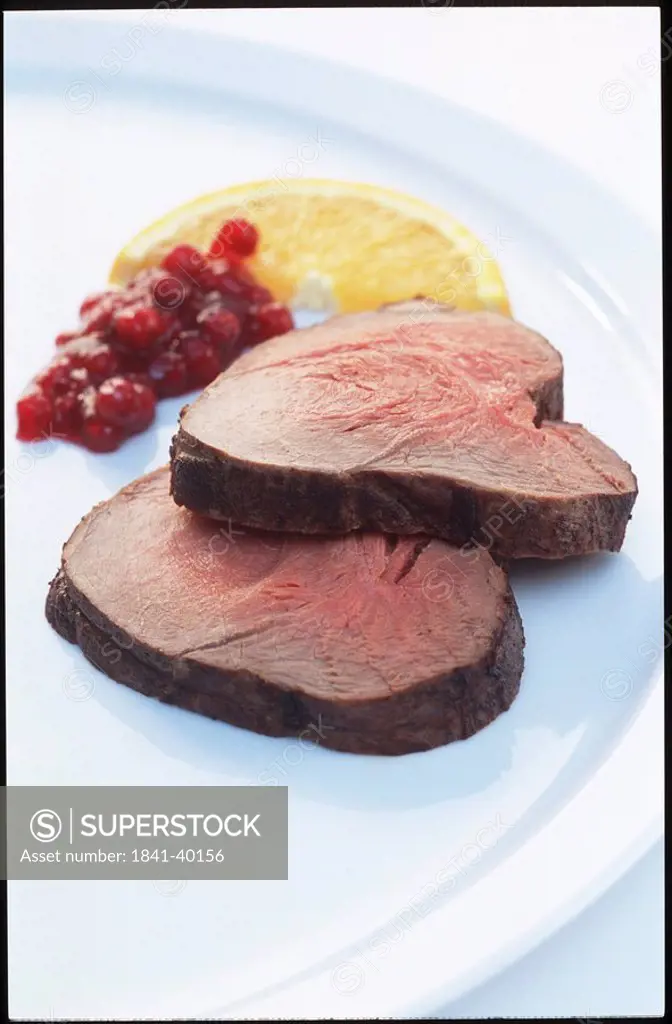 Roast beef, cranberry sauce and slice of orange on plate