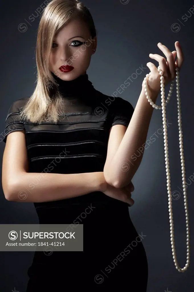 Young woman holding pearl necklace in her hand