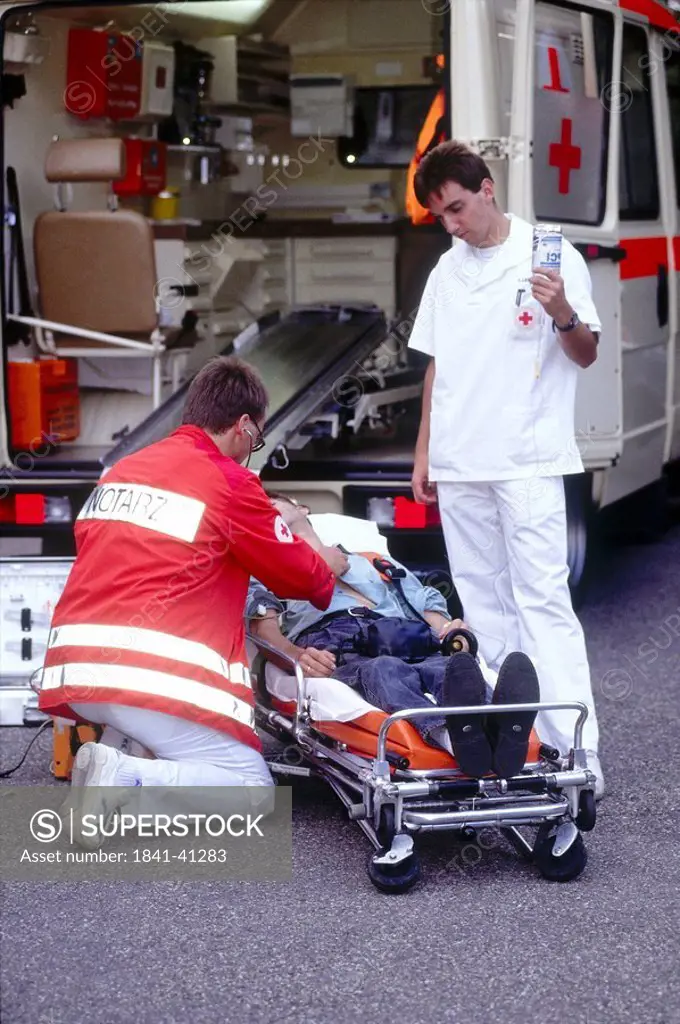 Doctor examining patient on stretcher in front of an ambulance