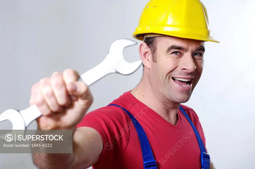 Portrait of man holding wrench and smiling
