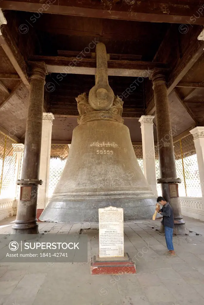 Man praying in front of old bell, Mingun Bell, Amarapura, Myanmar