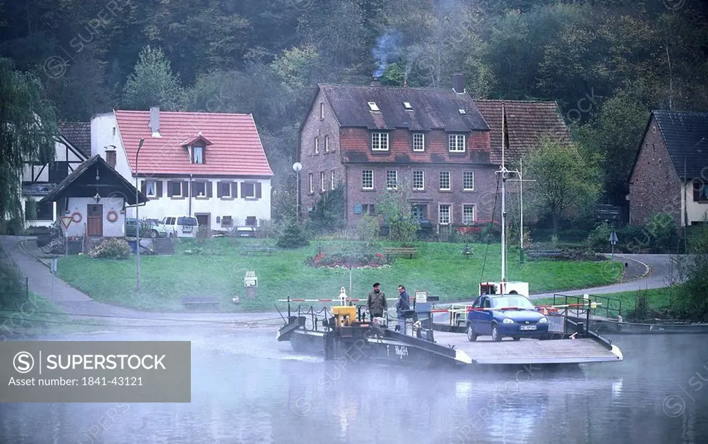 Two people and car on boat in river, River Neckar, Heidelberg, Germany