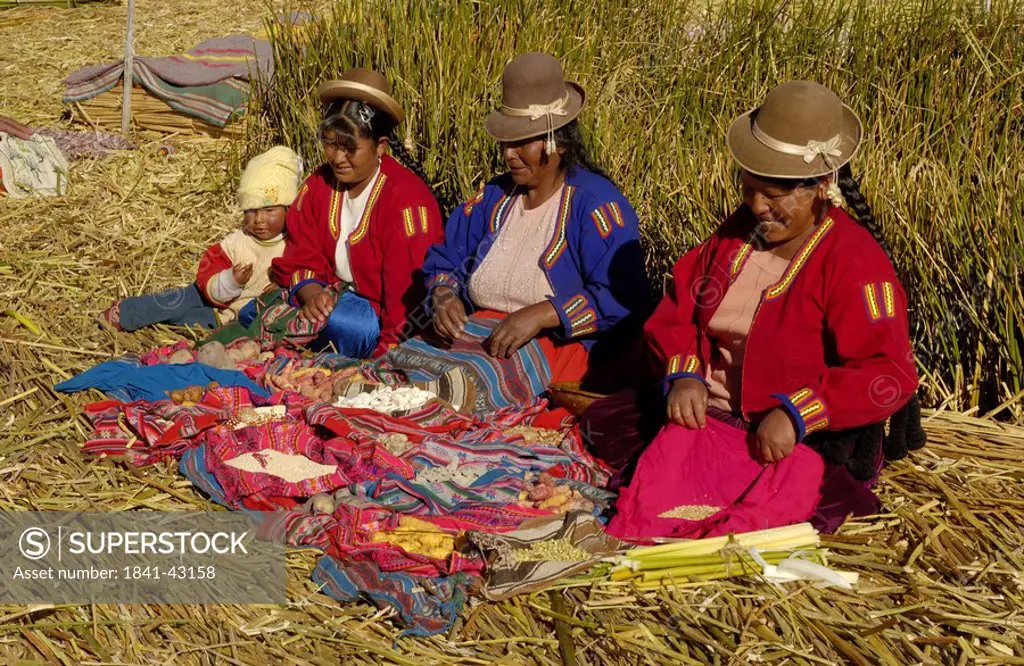 Uros women in traditional clothing doing needlework, Uros Floating Island, Lake Titicaca, Peru
