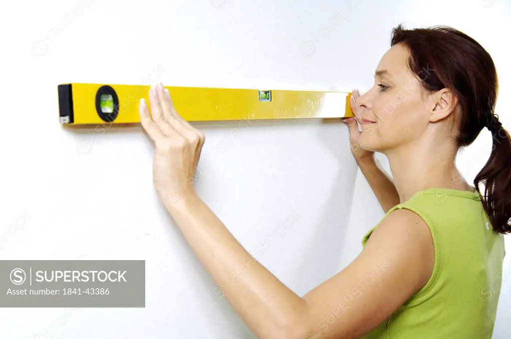 Close_up of woman using spirit level on wall