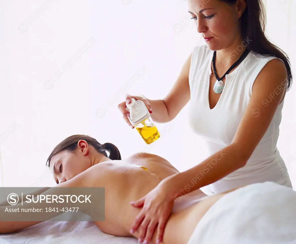 Rear view of young woman getting back massage from massage therapist