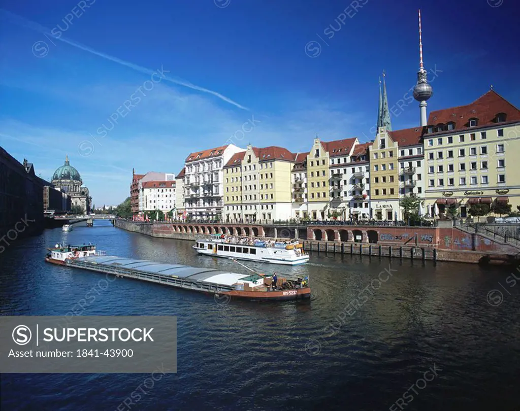 Freighter sailing on river in front of buildings in city, River Spree, Nicolaiviertel, Berlin, Germany