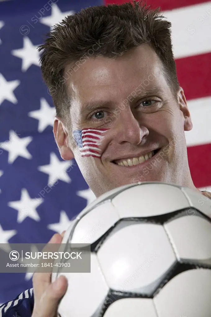 Portrait of male soccer fan holding soccer ball and smiling