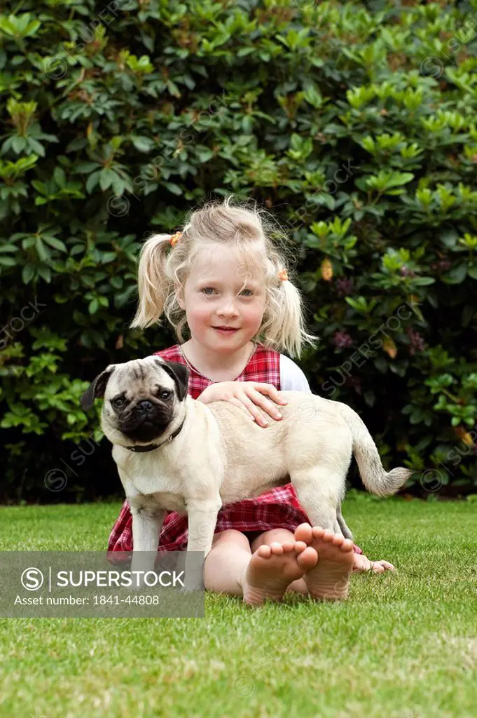 Girl sitting with pug on lawn