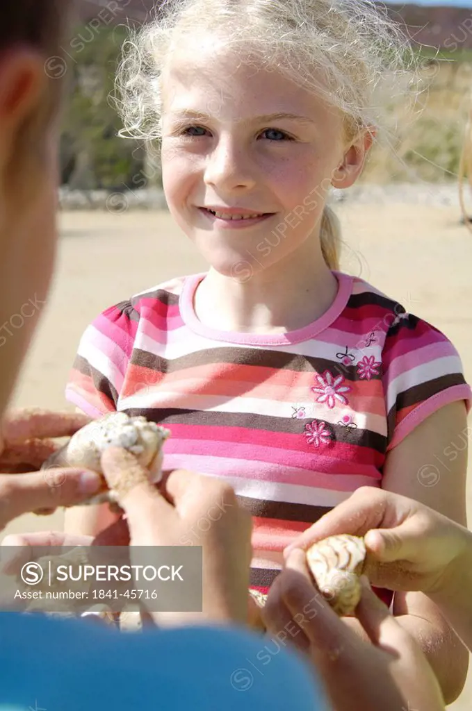Close_up of girl looking at boy holding shell on beach
