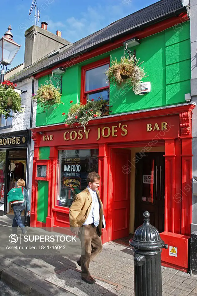 Two people walking in front of bar on street, Bridge Street, Republic of Ireland