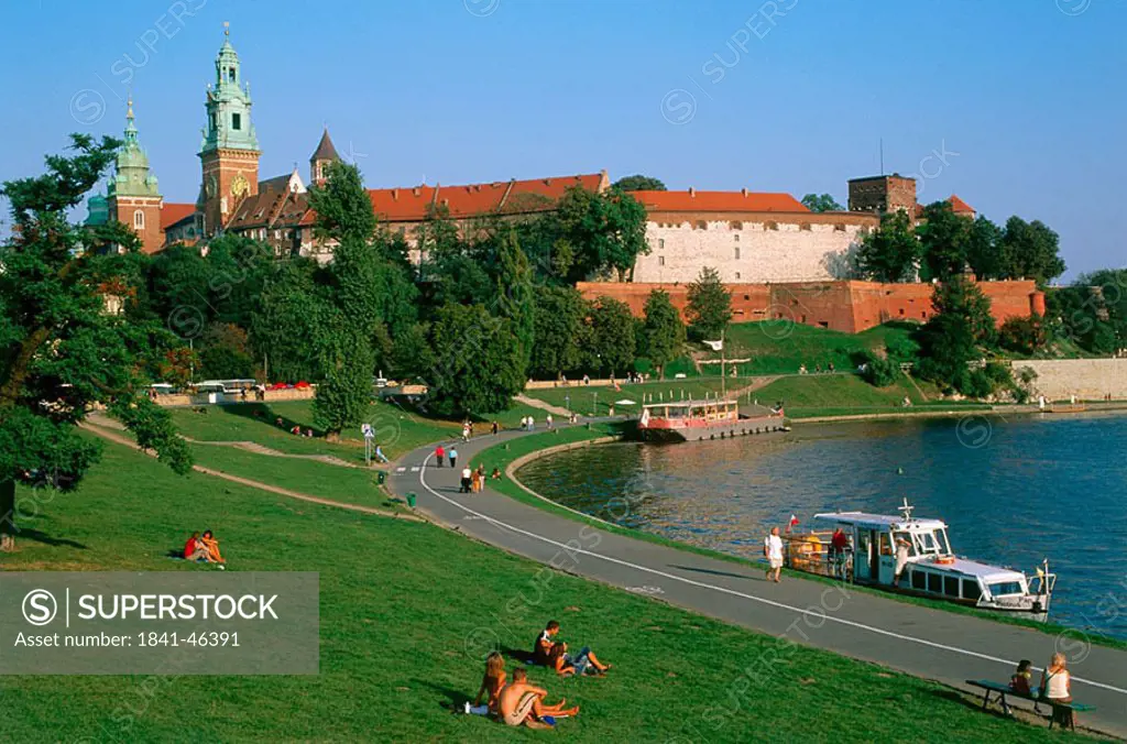 Tourists at riverside and castle in background, Wawel Castle, Krakow, Poland