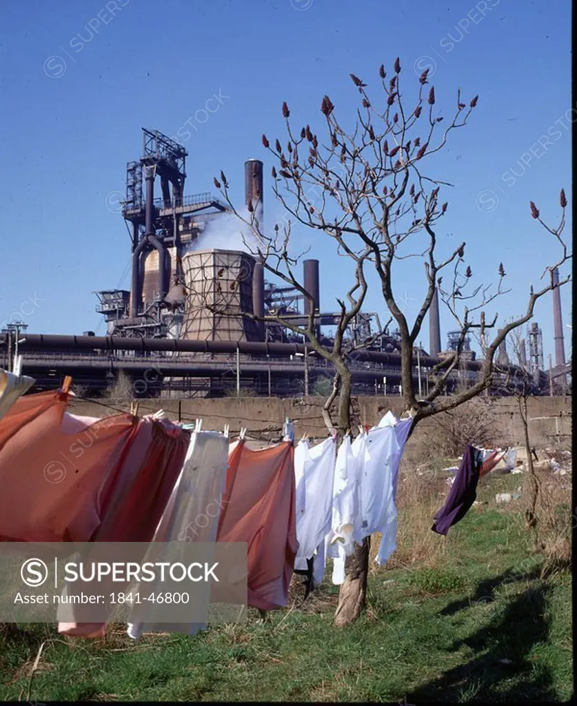 Clothes drying on clothesline with smelting plant in background, Germany
