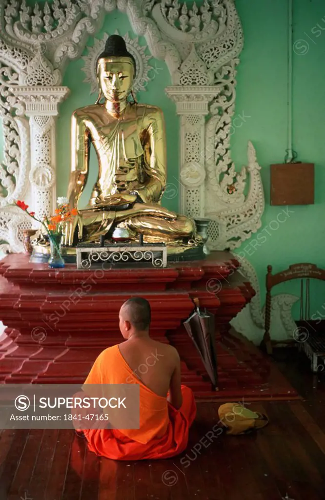 Rear view of monk praying in temple, Shwedagon Pagoda, Yangon, Myanmar