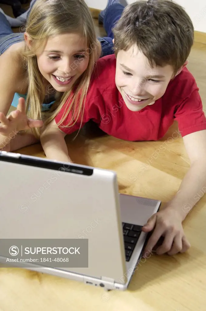 High angle view of brother and sister looking at laptop and smiling