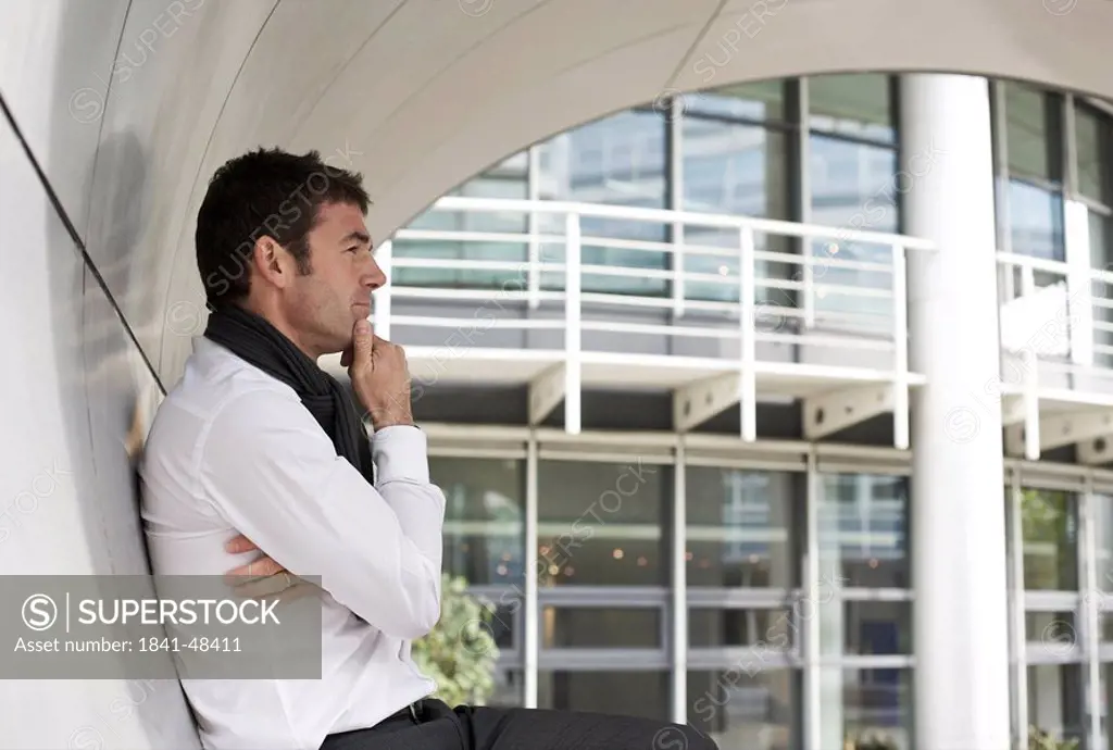 Thoughtful businessman standing in archway, side view