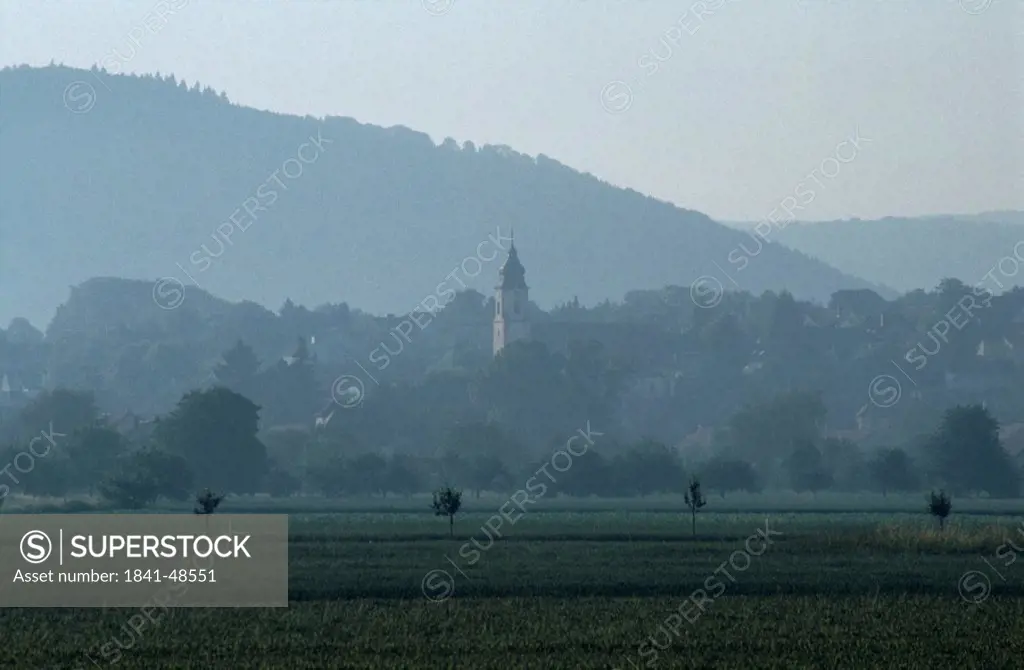 Field with bell tower in background, Germany