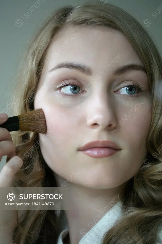 Young woman powdering face