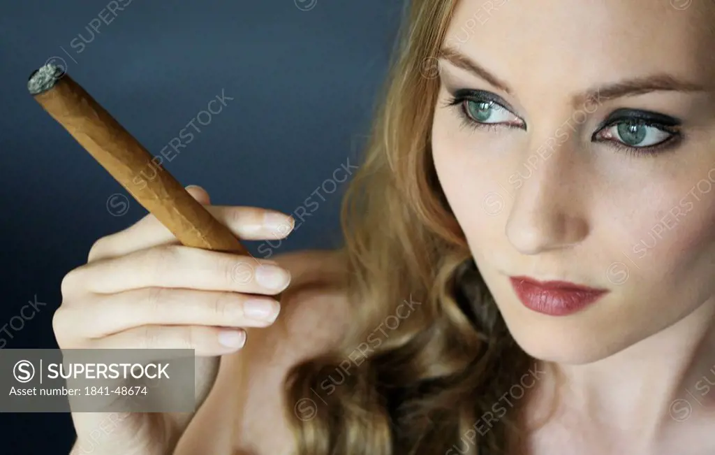Close_up of young woman smoking cigar