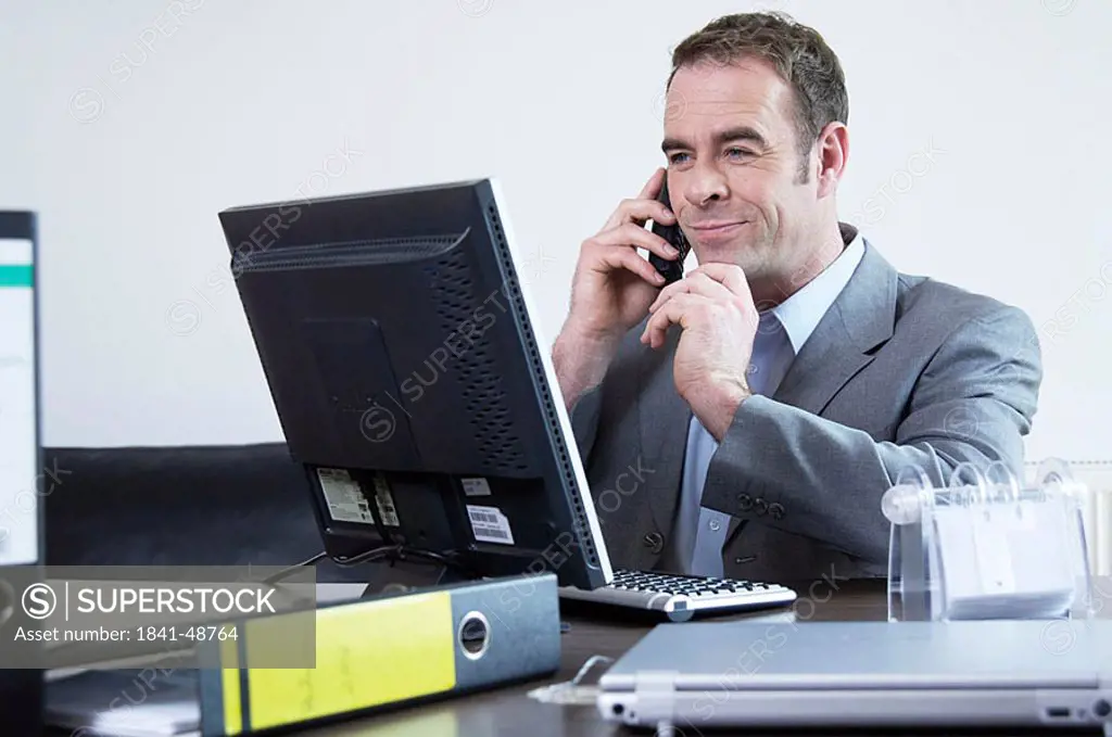 Businessman using computer and mobile phone