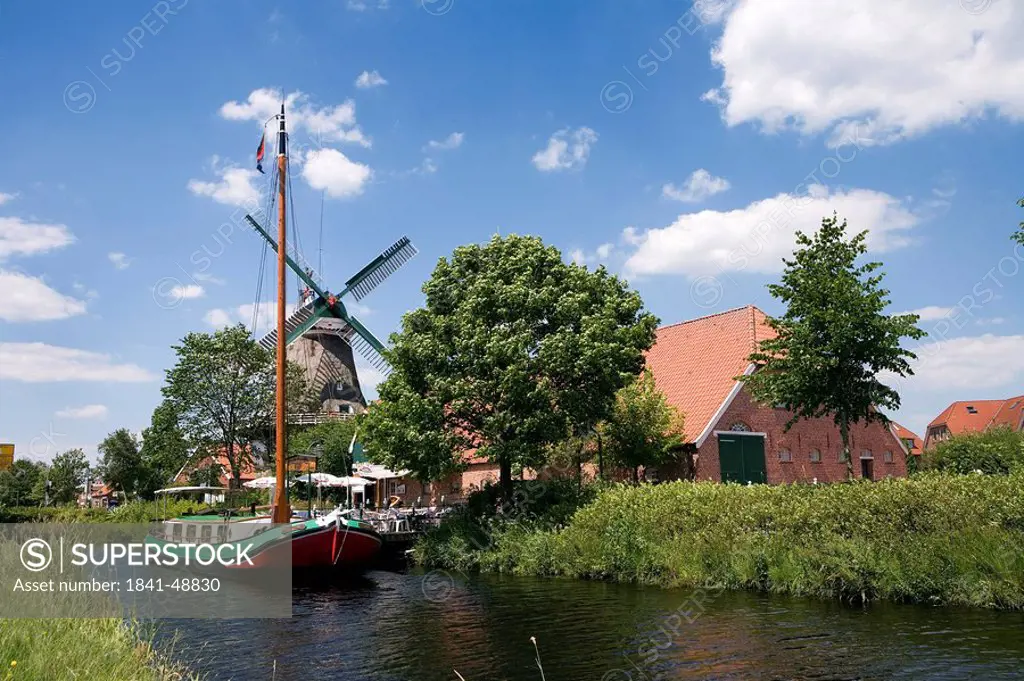 Sailboat in canal with industrial windmill in background, Ostgrossefehn, Lower Saxony, Germany