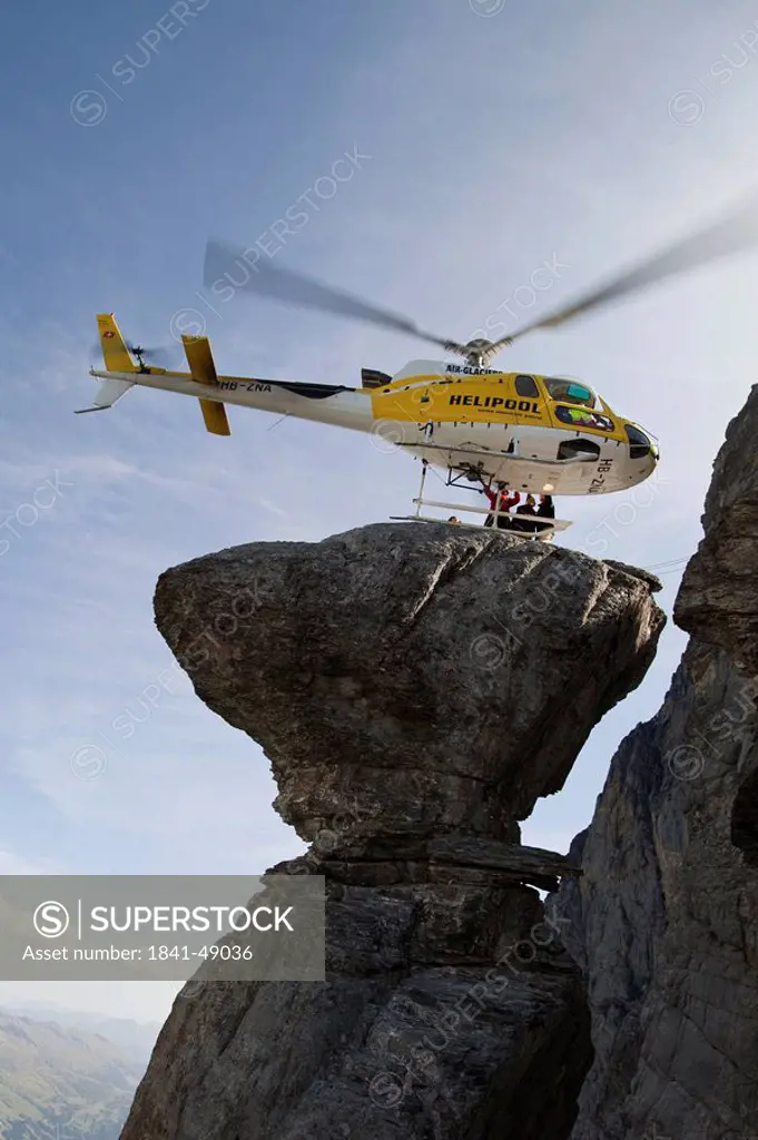 Basejumpers reaching rock formation with helicopter, Eiger North Face, Switzerland