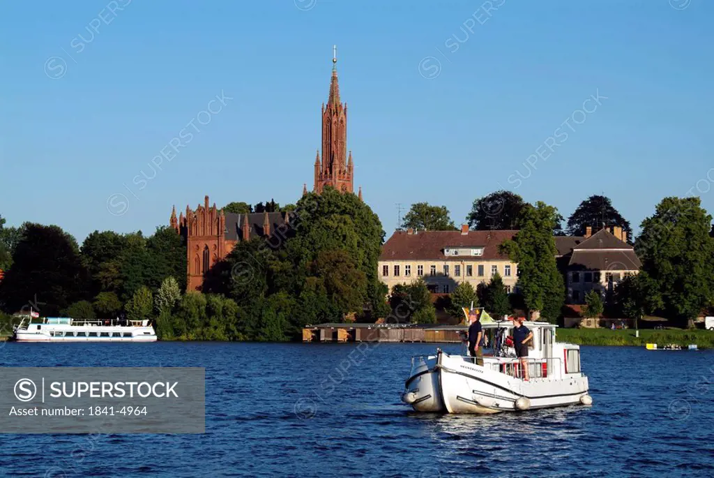 People on a boat, monastery church in the background, Malchow, Mecklenburg_Western Pomerania, Germany