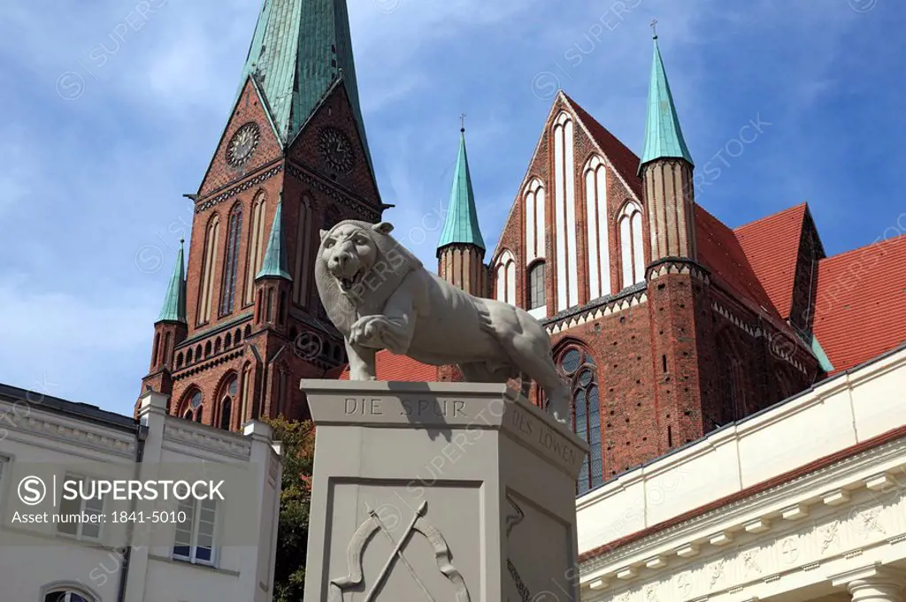 Lion sculpture with cathedral in the background, Schwerin, Germany, low angle view