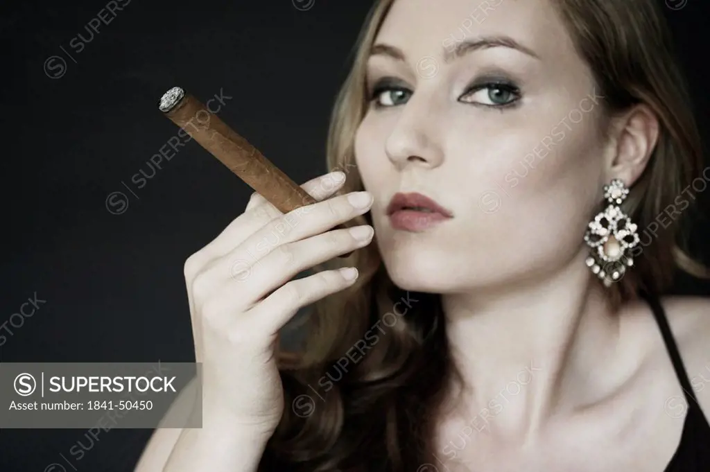 Portrait of young woman smoking cigar