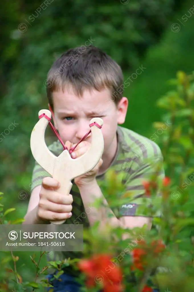 Close_up of boy using slingshot in field
