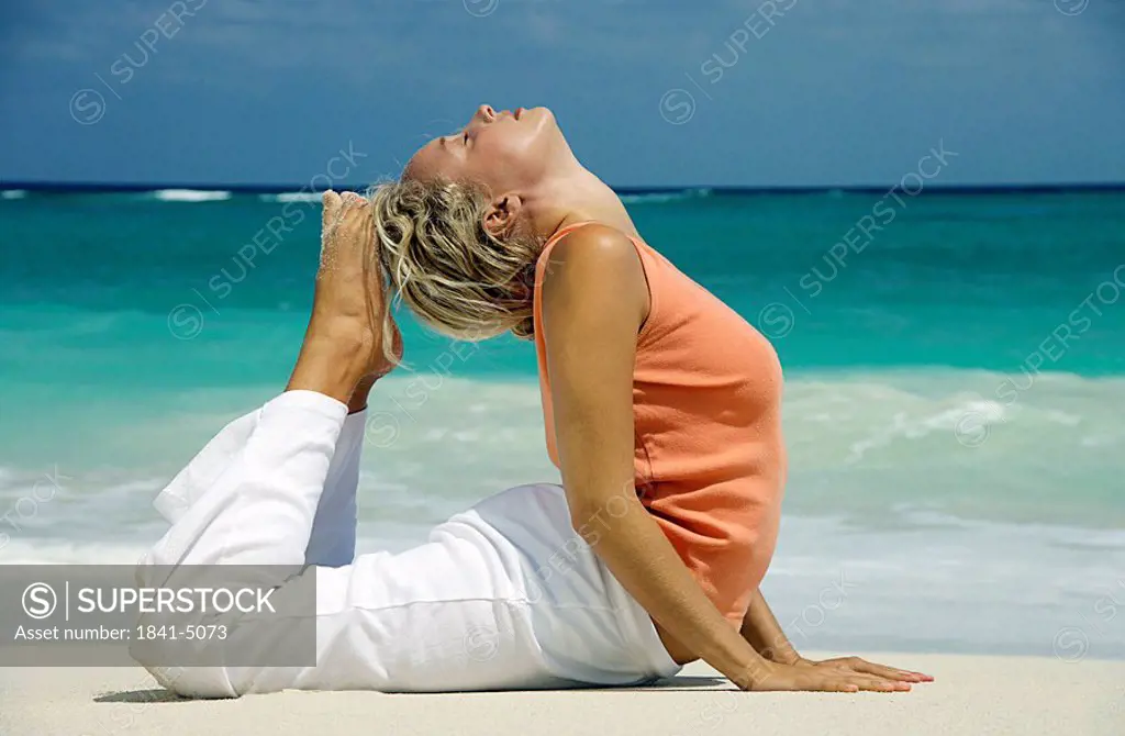 Woman practising yoga on a beach, Paradise Island, Bahamas, side view