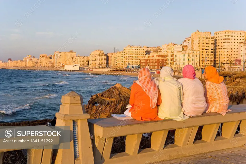 Rear view of women sitting on bench at coast, Corniche, Alexandria, Egypt