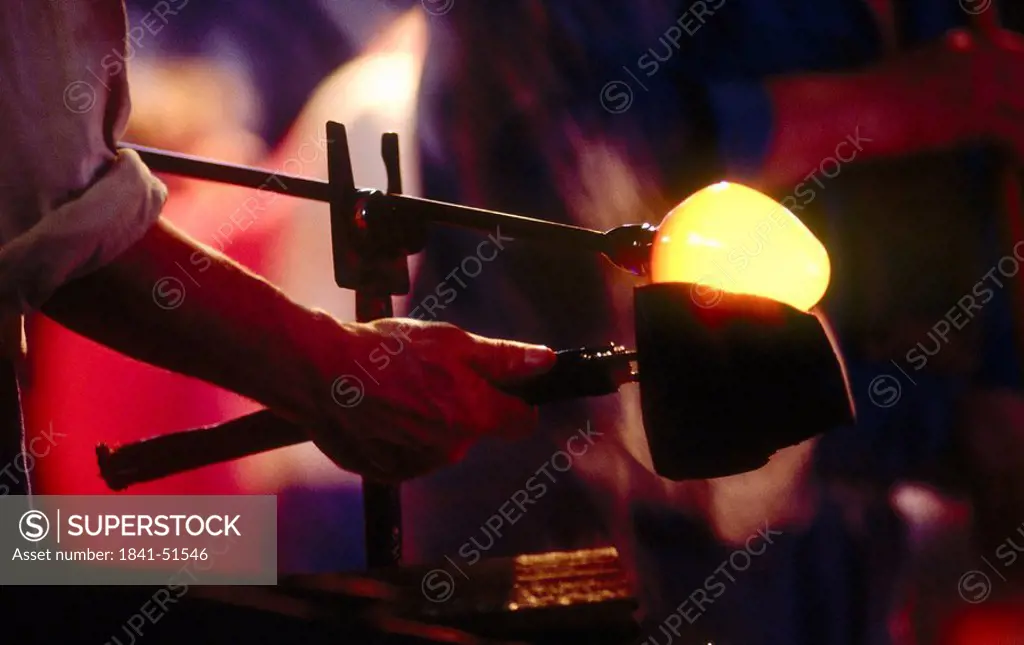 Mid section view of man blowing glass