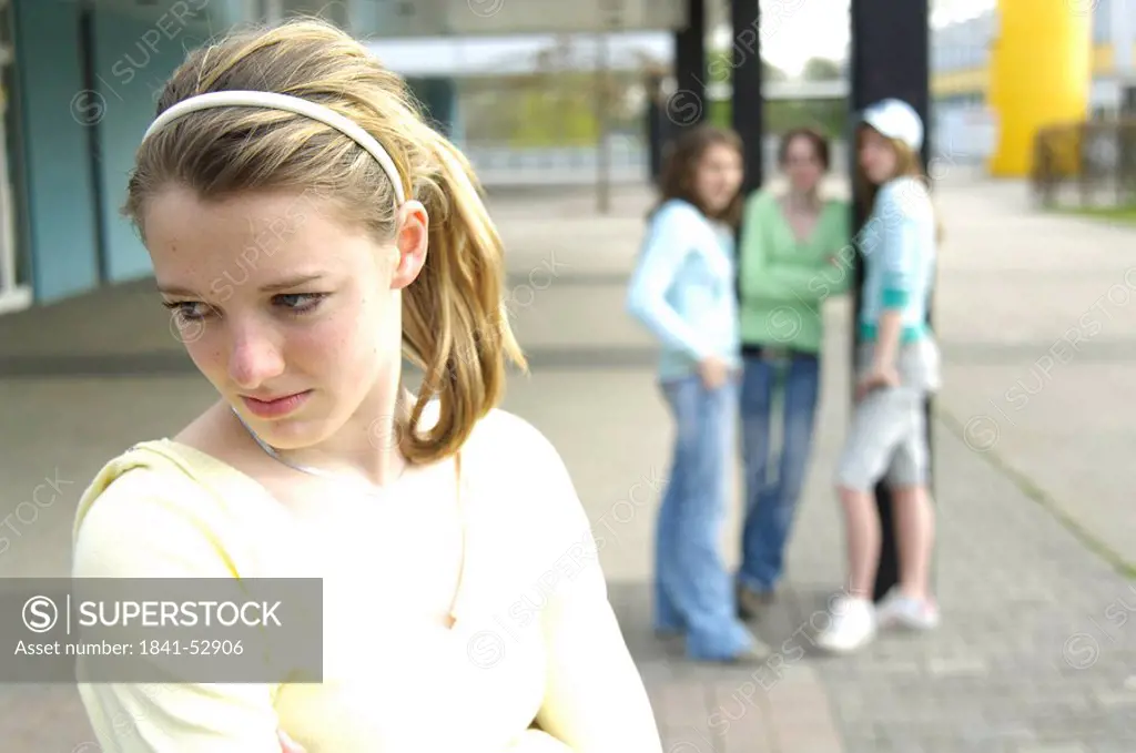 Close_up of teenage girl looking sad with her friends standing in background