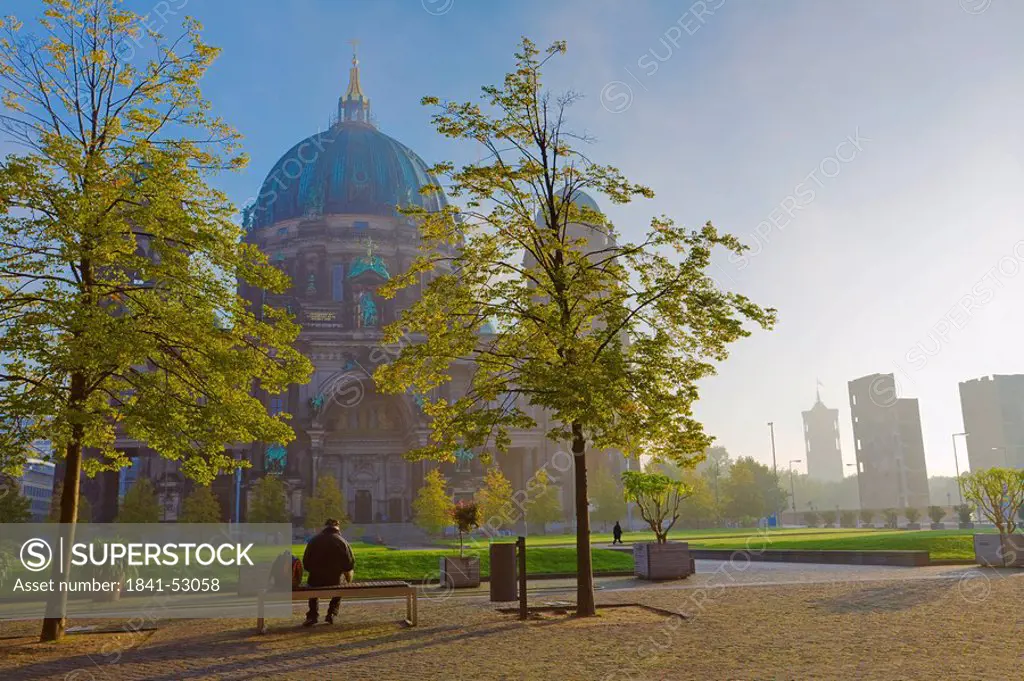 Rear view of person sitting on bench, Lustgarten, Berlin Cathedral, Berlin, Germany