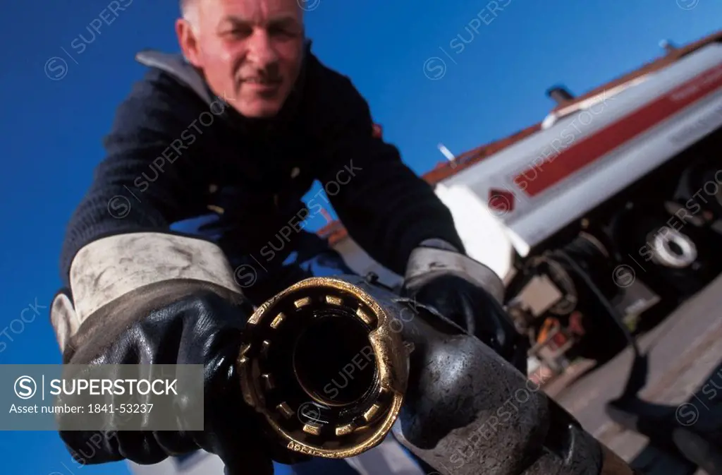 Close_up of man holding oil nozzle