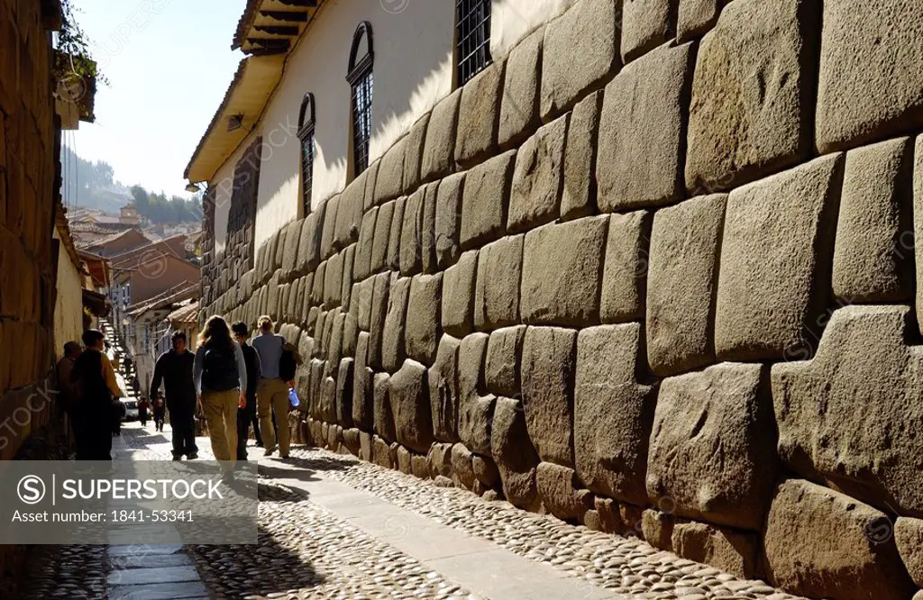 Tourists walking near stone wall, Inca Ruins, Machu Picchu, Cusco Region, Peru