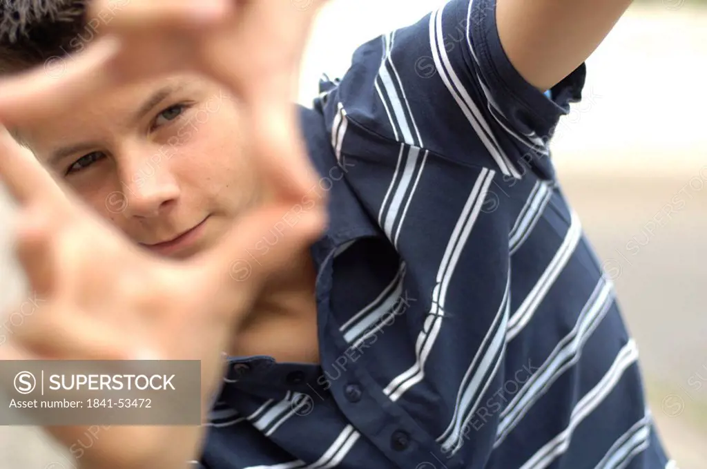 Portrait of teenage boy looking through finger frame