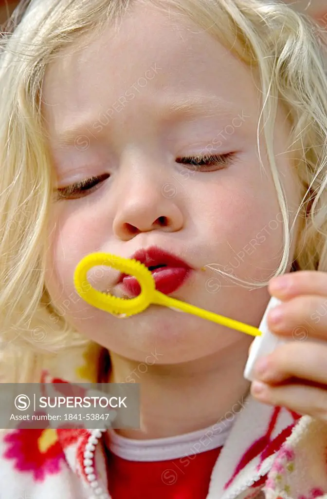 Blond girl blowing bubbles