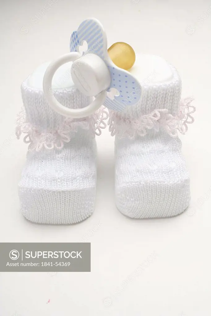 Close_up of pair of baby booties and pacifier